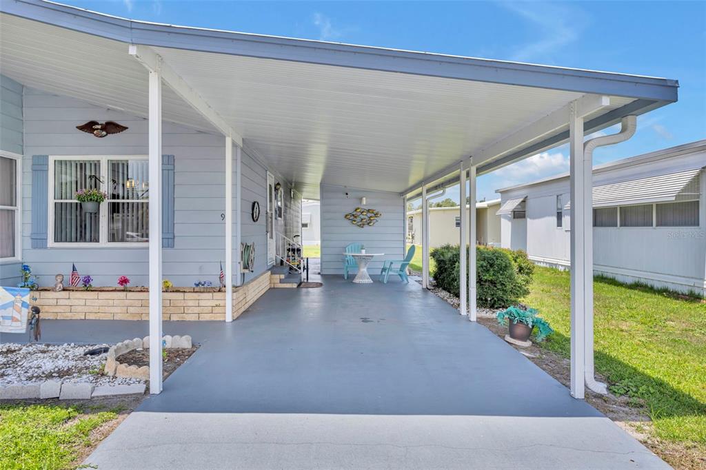 A light blue mobile home features a covered carport with a concrete floor and patio — 91 MAUNA LOA DRIVE, LEESBURG, FL