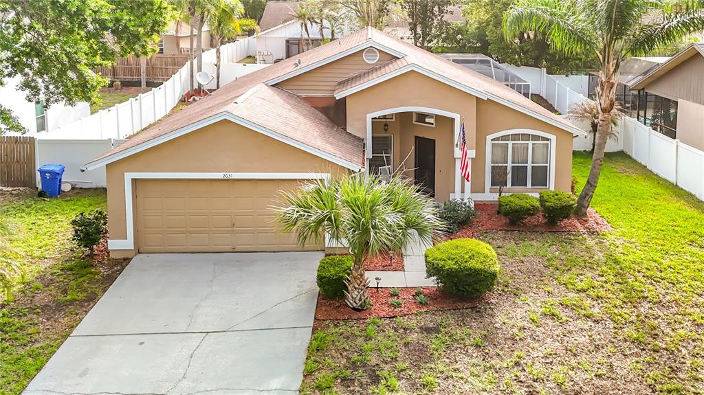 An exterior view of a tan single-story house with a garage and a palm tree — 2631 GREEN VALLEY STREET, VALRICO, FL