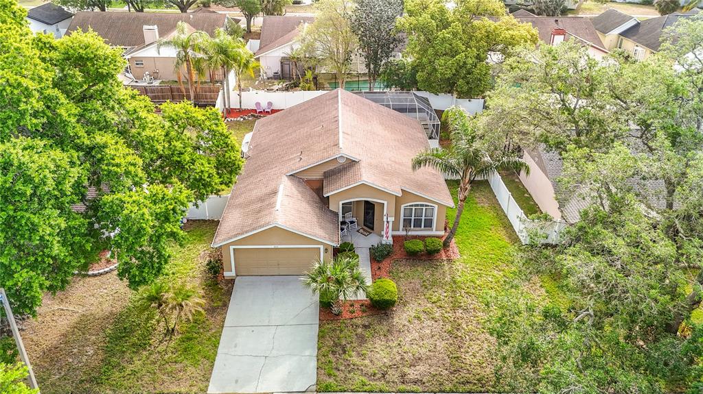 An aerial view shows a single-story suburban house with a tan exterior and a garage — 2631 GREEN VALLEY STREET, VALRICO, FL