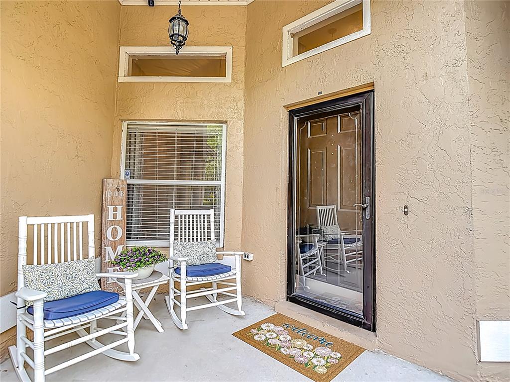 A covered porch features two white rocking chairs, a small table, and a glass storm door — 2631 GREEN VALLEY STREET, VALRICO, FL