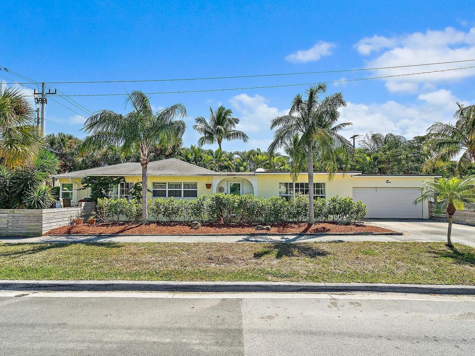 A single-story yellow house with a two-car garage, palm trees, and a landscaped front yard — 400 45th Street, West Palm Beach FL 33407, WEST PALM BEACH, FL
