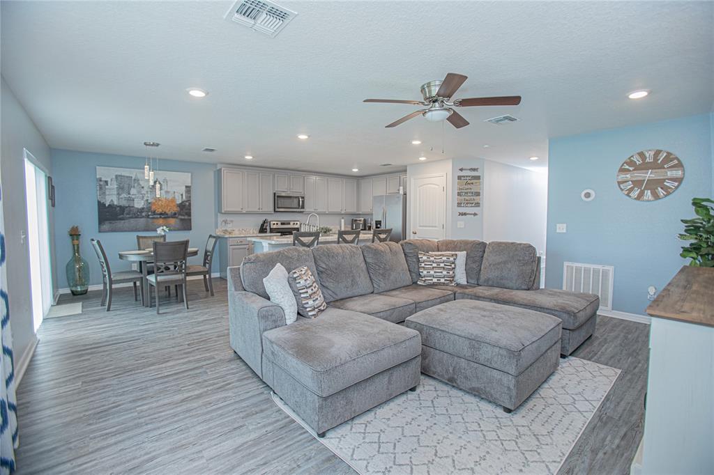 An open-concept living room and kitchen featuring gray flooring, a sectional sofa, and dining area — 214 LINDA LANE, AUBURNDALE, FL