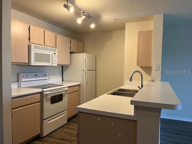 A kitchen features light wood cabinets, white appliances, and a breakfast bar with a sink — 5447 VINELAND ROAD UNIT 1210, ORLANDO, FL