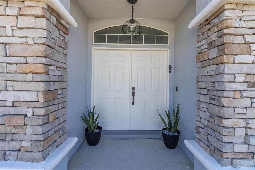 A front entryway features double white doors flanked by stone columns and potted snake plants — 3419 PATTERSON HEIGHTS DRIVE, HAINES CITY, FL