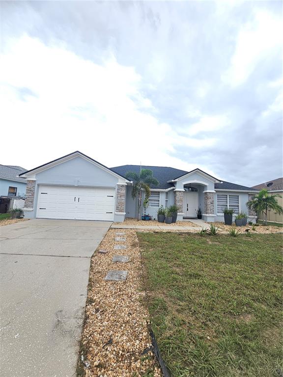 A single-story house with a light blue exterior, stone accents, and a two-car garage — 3419 PATTERSON HEIGHTS DRIVE, HAINES CITY, FL