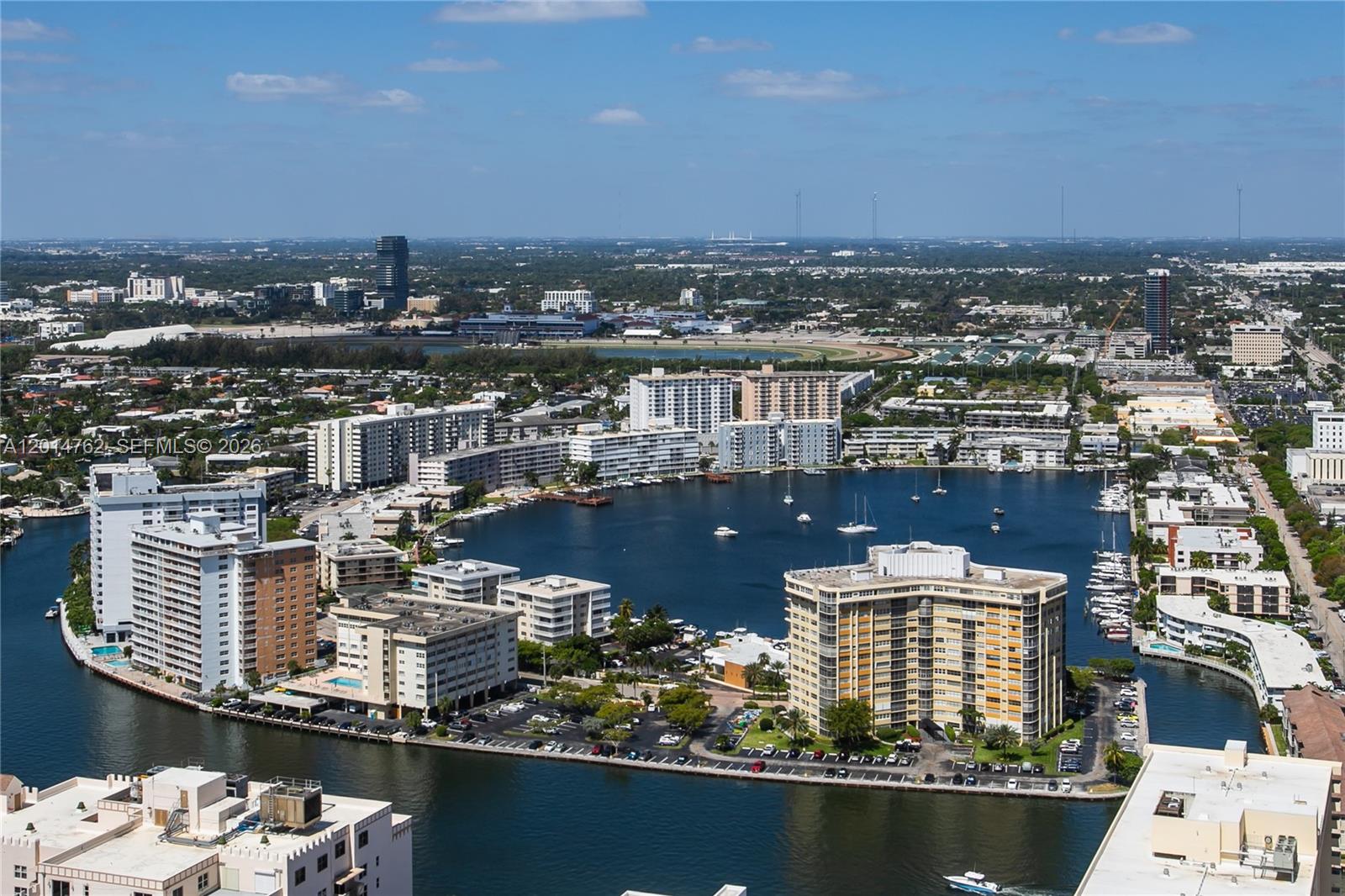 An aerial view shows high-rise residential buildings surrounding a large, boat-filled lake in a city — 1830 S Ocean Dr # 4504, Hallandale Beach FL 33009, HALLANDALE BEACH, FL