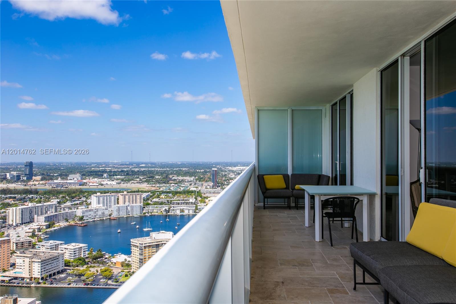 A high-rise balcony features outdoor seating, a small table, and a panoramic city view — 1830 S Ocean Dr # 4504, Hallandale Beach FL 33009, HALLANDALE BEACH, FL