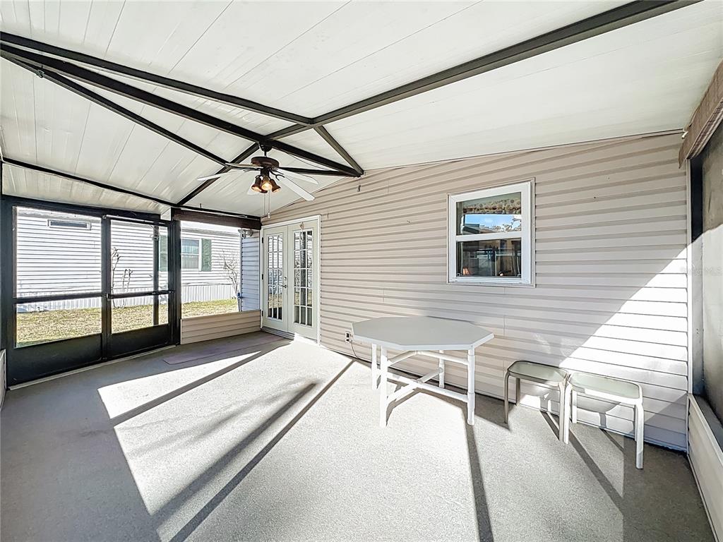 A screened-in porch features a ceiling fan, a white table, and two chairs — 698 CINDI AVENUE, LEESBURG, FL