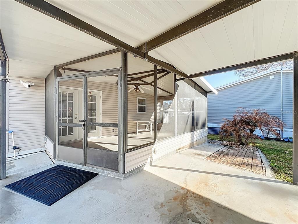 A screened-in porch with a concrete floor sits adjacent to a covered outdoor patio area — 698 CINDI AVENUE, LEESBURG, FL