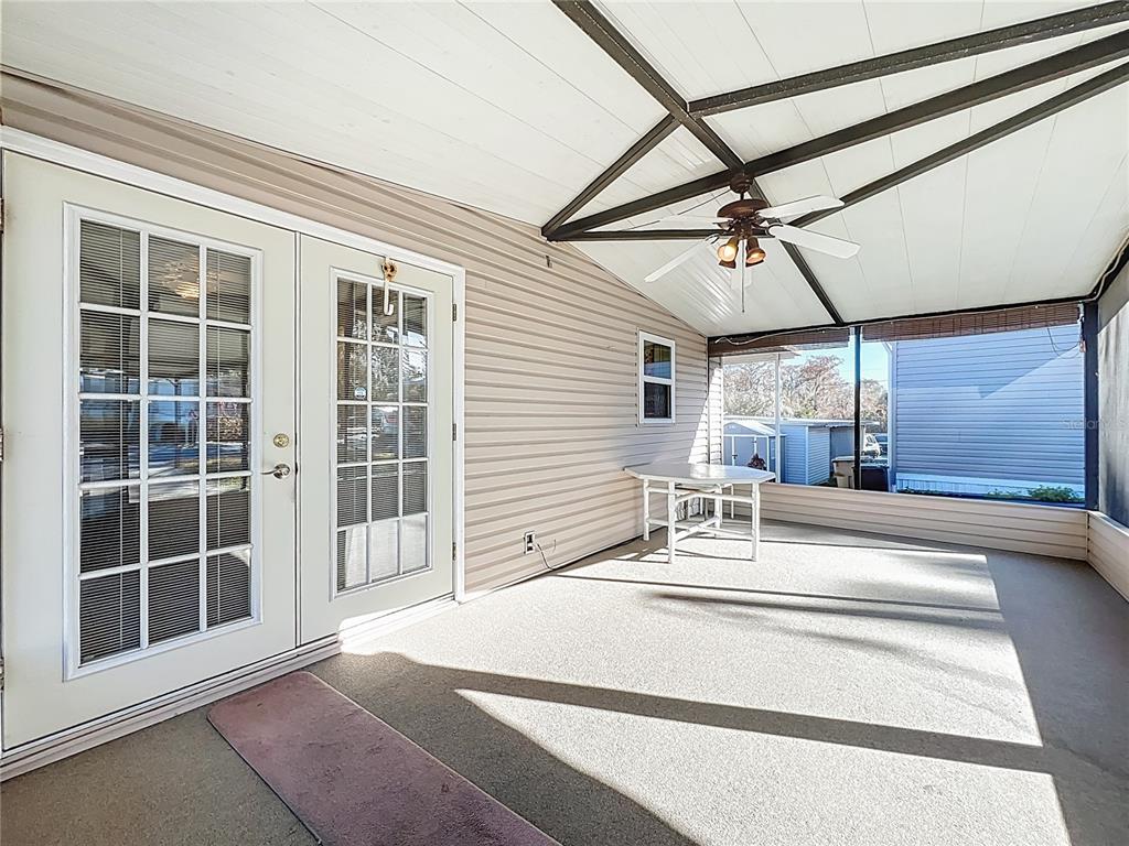 A covered patio features light-colored siding, a ceiling fan, and double glass doors — 698 CINDI AVENUE, LEESBURG, FL