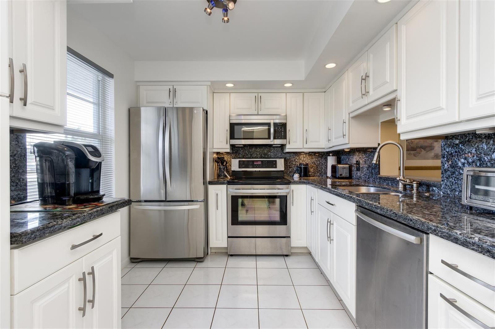 A kitchen with white cabinets, stainless steel appliances, and dark granite countertops — 190 SE 5th Avenue # 108, Dania Beach FL 33004, DANIA BEACH, FL