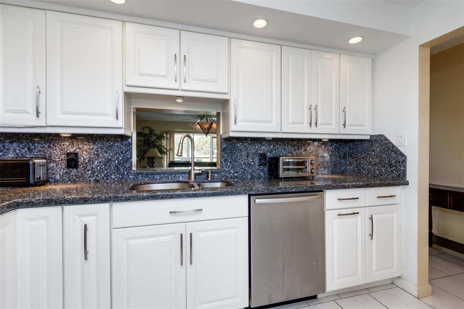 A kitchen features white cabinets, dark granite countertops, a stainless steel dishwasher, and a pass-through — 190 SE 5th Avenue # 108, Dania Beach FL 33004, DANIA BEACH, FL