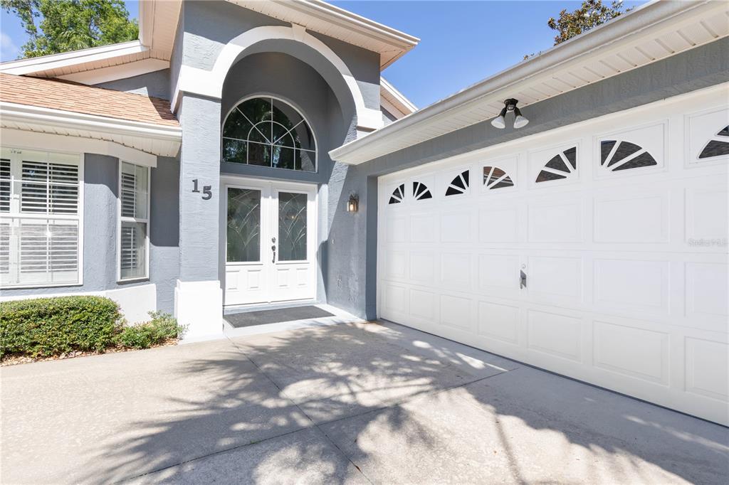 The exterior of a house features a gray facade, a white garage door, and double doors — 15 TANGLEWOOD COURT, PALM COAST, FL