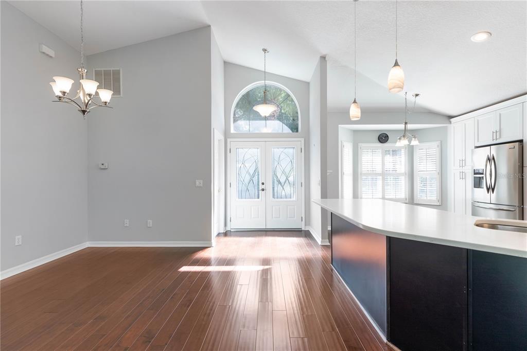 A bright dining area with hardwood floors, a chandelier, and double front doors with glass — 15 TANGLEWOOD COURT, PALM COAST, FL