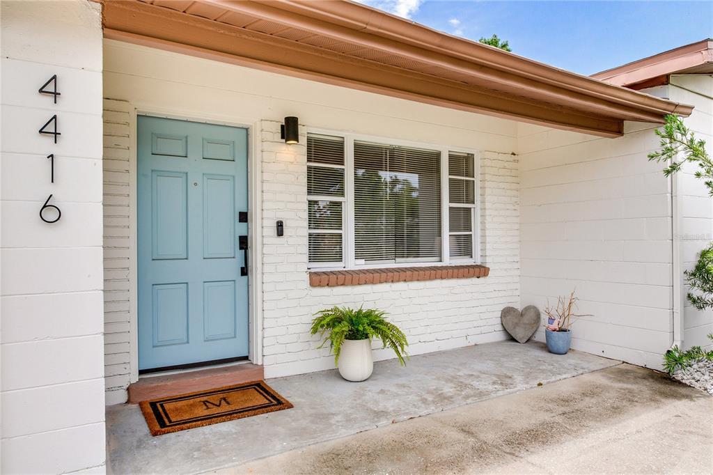 A light blue front door sits next to a window on a white brick porch — 4416 W BAY COURT AVE, TAMPA, FL