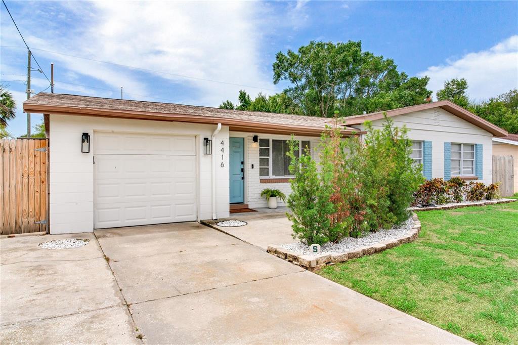 A single-story house with a white brick exterior, a light blue door, and a concrete driveway — 4416 W BAY COURT AVE, TAMPA, FL