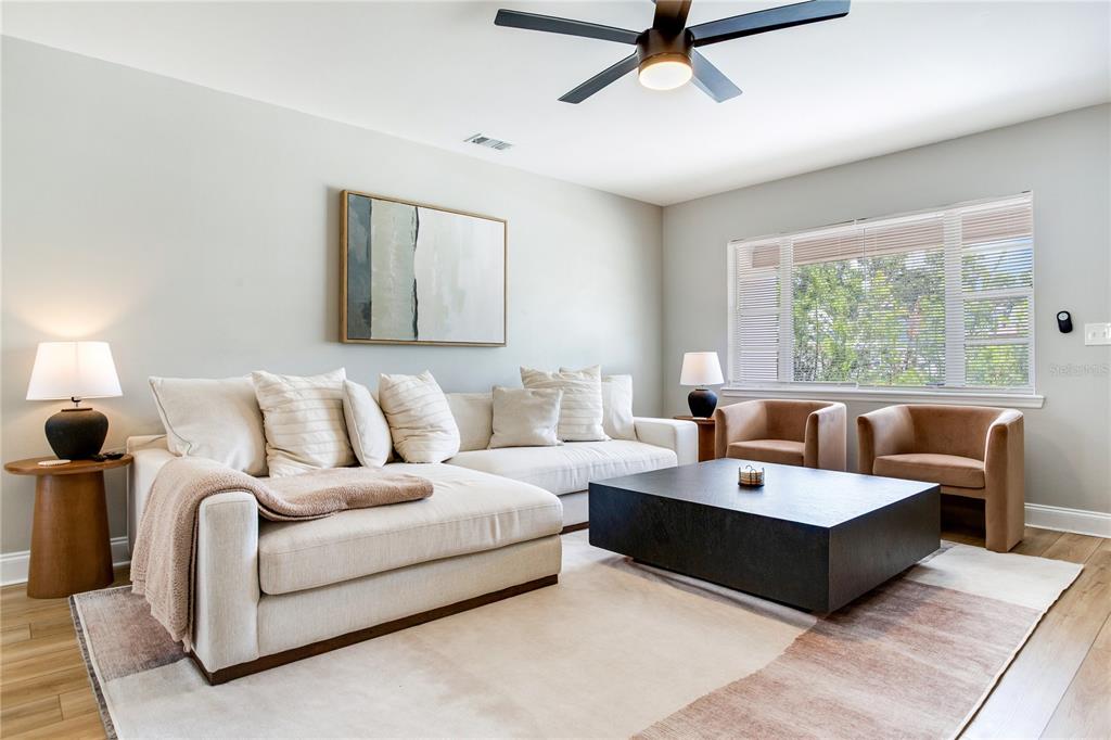 A living room features a cream sectional sofa, a black coffee table, and two armchairs — 4416 W BAY COURT AVE, TAMPA, FL