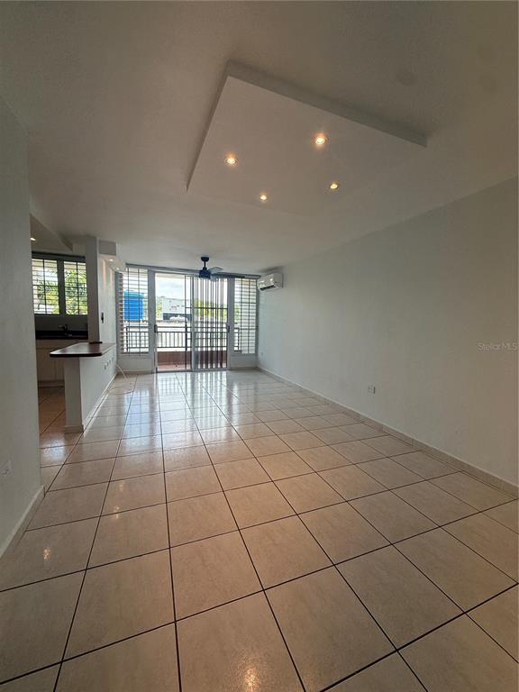 An open-concept living area features light-colored tile floors, a recessed ceiling panel, and a balcony — 109 CALLE PLUMOSO REAL UNIT E212, GUAYNABO, PR