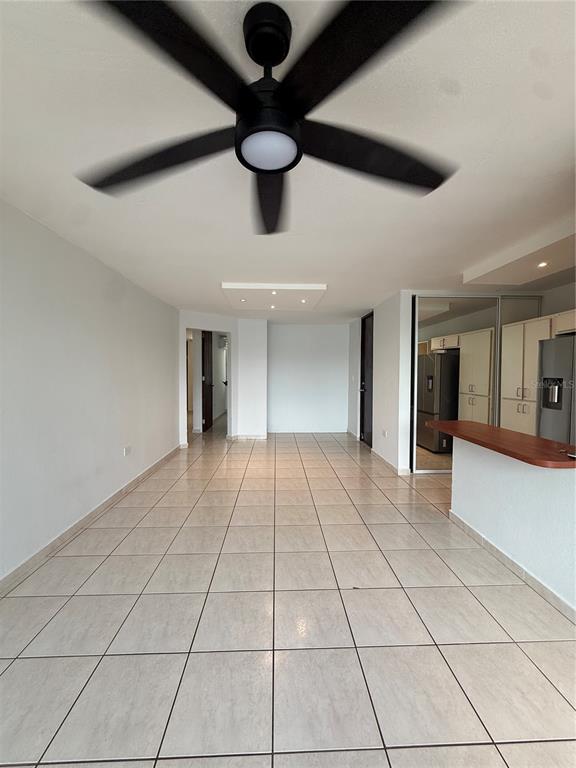 An open-concept living area features light tile flooring, a ceiling fan, and a kitchen counter — 109 CALLE PLUMOSO REAL UNIT E212, GUAYNABO, PR
