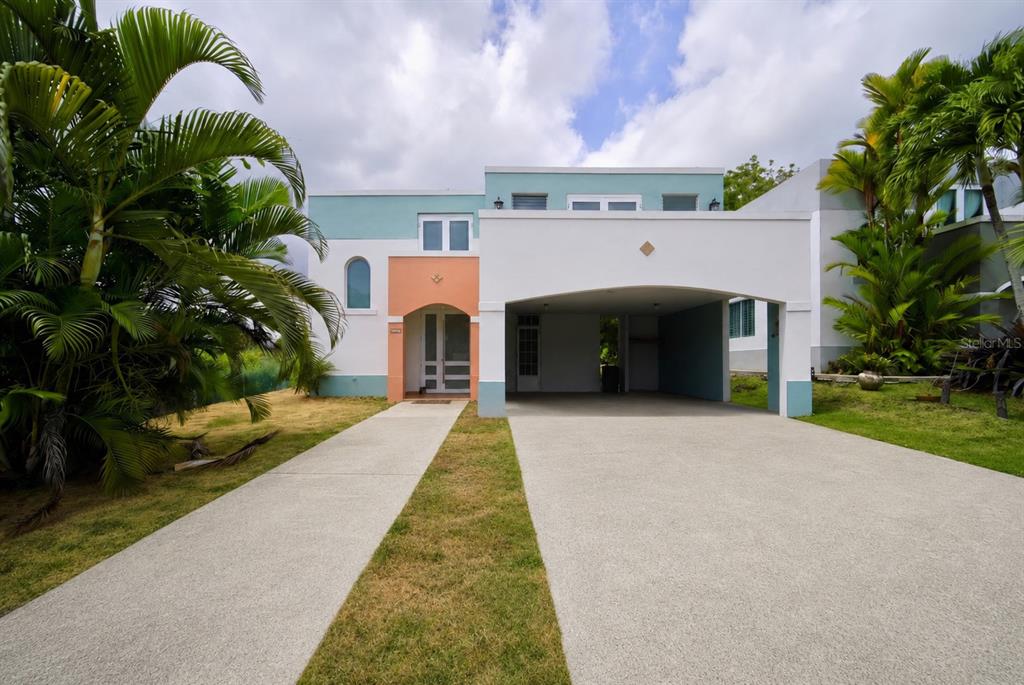 A two-story house features a white facade, a peach-colored entryway, and a large attached carport — D-17 URB. VISTA VERDE, FAJARDO, PR