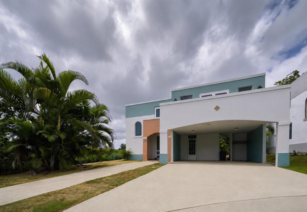 A two-story house with a white stucco facade, a carport, and teal-colored accents — D-17 URB. VISTA VERDE, FAJARDO, PR