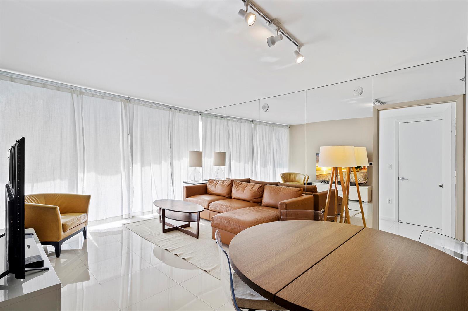 A living room features a leather sectional, a round dining table, and a mirrored wall — 495 Brickell Avenue # 911, Miami FL 33131, MIAMI, FL