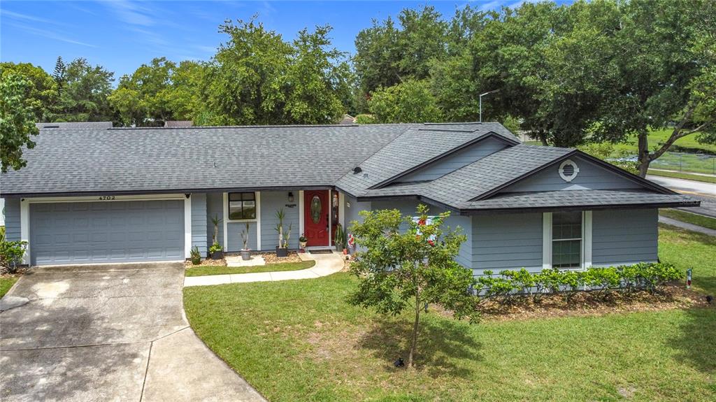 A single-story blue house with a gray shingled roof, a garage, and a front lawn — 4702 HOPESPRING DRIVE, ORLANDO, FL