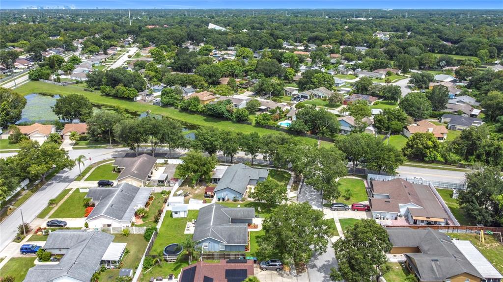 An aerial view shows a suburban neighborhood with single-family homes, green lawns, and trees — 4702 HOPESPRING DRIVE, ORLANDO, FL