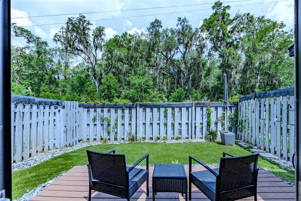 A small backyard features a wooden deck with two chairs, artificial turf, and a wooden fence — 4460 SW 20TH LANE, GAINESVILLE, FL