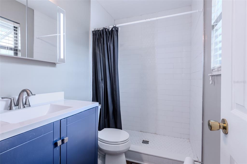 A bathroom features a blue vanity, a white sink, a toilet, and a tiled shower — 4460 SW 20TH LANE, GAINESVILLE, FL