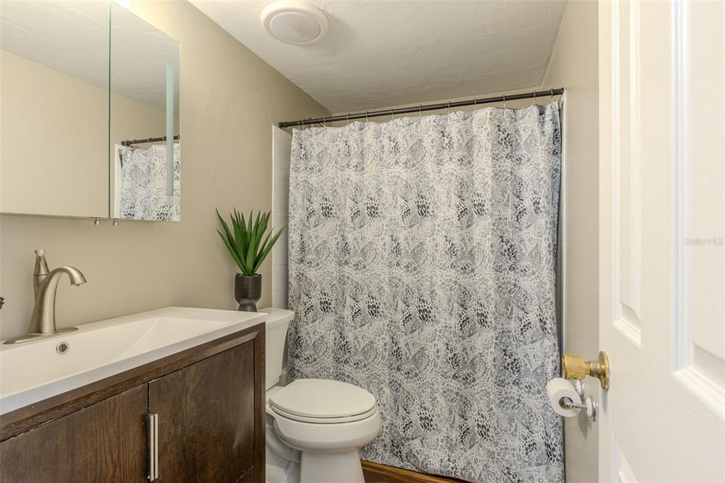 A bathroom features a dark wood vanity, a white toilet, and a patterned shower curtain — 4460 SW 20TH LANE, GAINESVILLE, FL