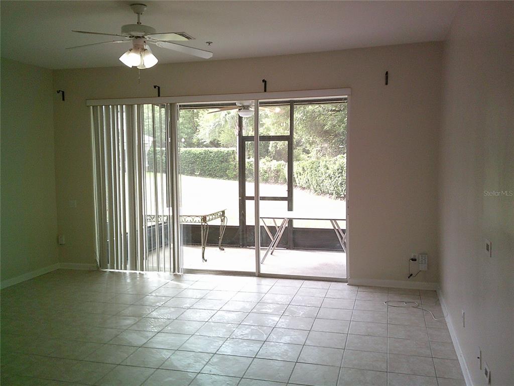 A tiled living room features a ceiling fan and sliding glass doors opening to a lanai — 6292 TWAIN STREET UNIT 107, ORLANDO, FL