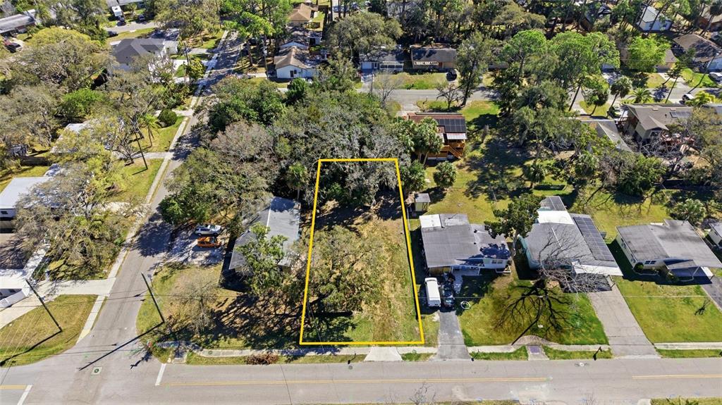 An aerial view shows a vacant, tree-covered residential lot outlined in yellow between two houses — 7214 OELSNER STREET, NEW PORT RICHEY, FL
