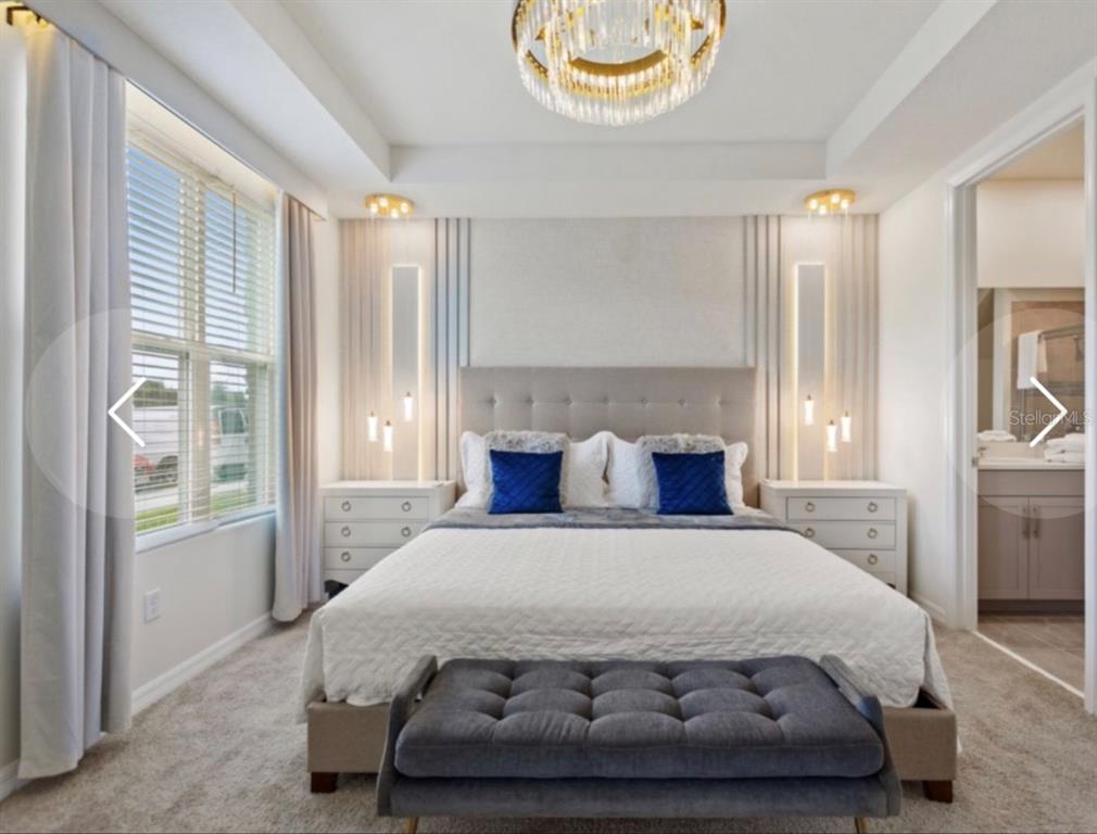 A bedroom features a tufted headboard, a central chandelier, and two bedside tables with lamps — 1692 TROPICAL PALMS CIRCLE, KISSIMMEE, FL