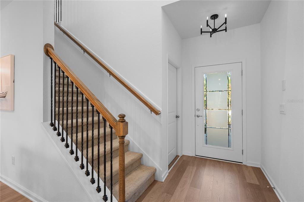 An entryway features a carpeted staircase with a wooden handrail, a white door, and flooring — 212 MISTY HARBOR TRACE, PALM COAST, FL