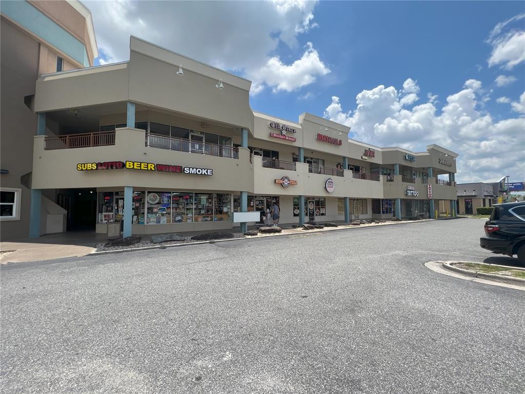 A multi-story commercial strip mall building with various storefronts under a blue sky — 7219 INTERNATIONAL DRIVE, ORLANDO, FL