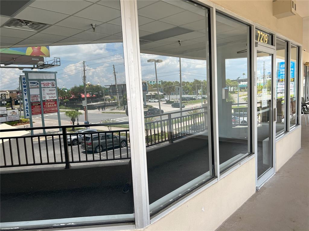 A view from a covered walkway looking through large glass windows into an empty storefront — 7219 INTERNATIONAL DRIVE, ORLANDO, FL