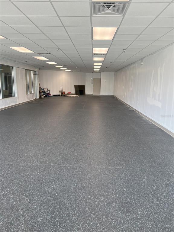 An empty commercial space features a gray speckled floor, white walls, and a drop ceiling — 7219 INTERNATIONAL DRIVE, ORLANDO, FL