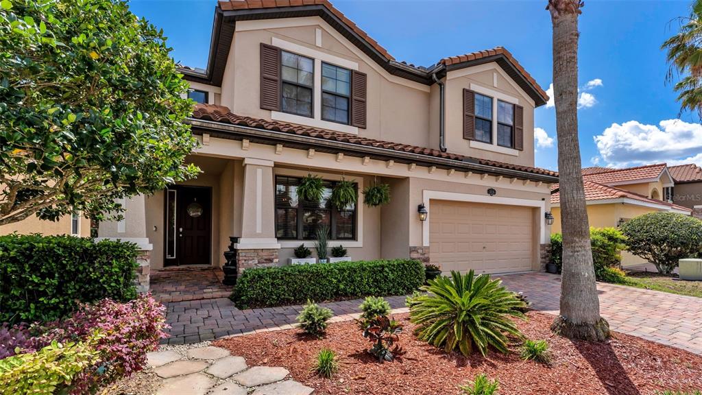 A two-story suburban house features a tan stucco exterior, a paved driveway, and landscaping — 1826 ALTAVISTA CIRCLE, LAKELAND, FL