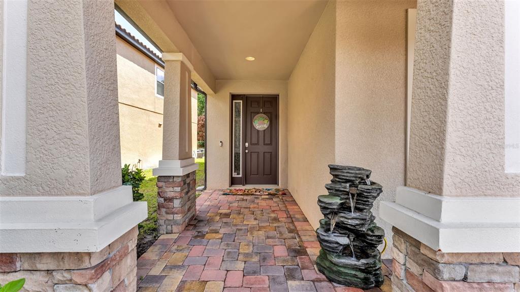 A covered entryway features a paver floor, stone-based columns, and a dark brown front door — 1826 ALTAVISTA CIRCLE, LAKELAND, FL