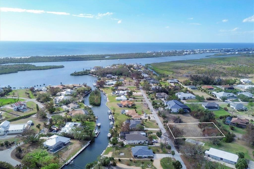 An aerial view shows a vacant residential lot outlined in white within a coastal neighborhood — 170 SPYGLASS ALLEY, PLACIDA, FL