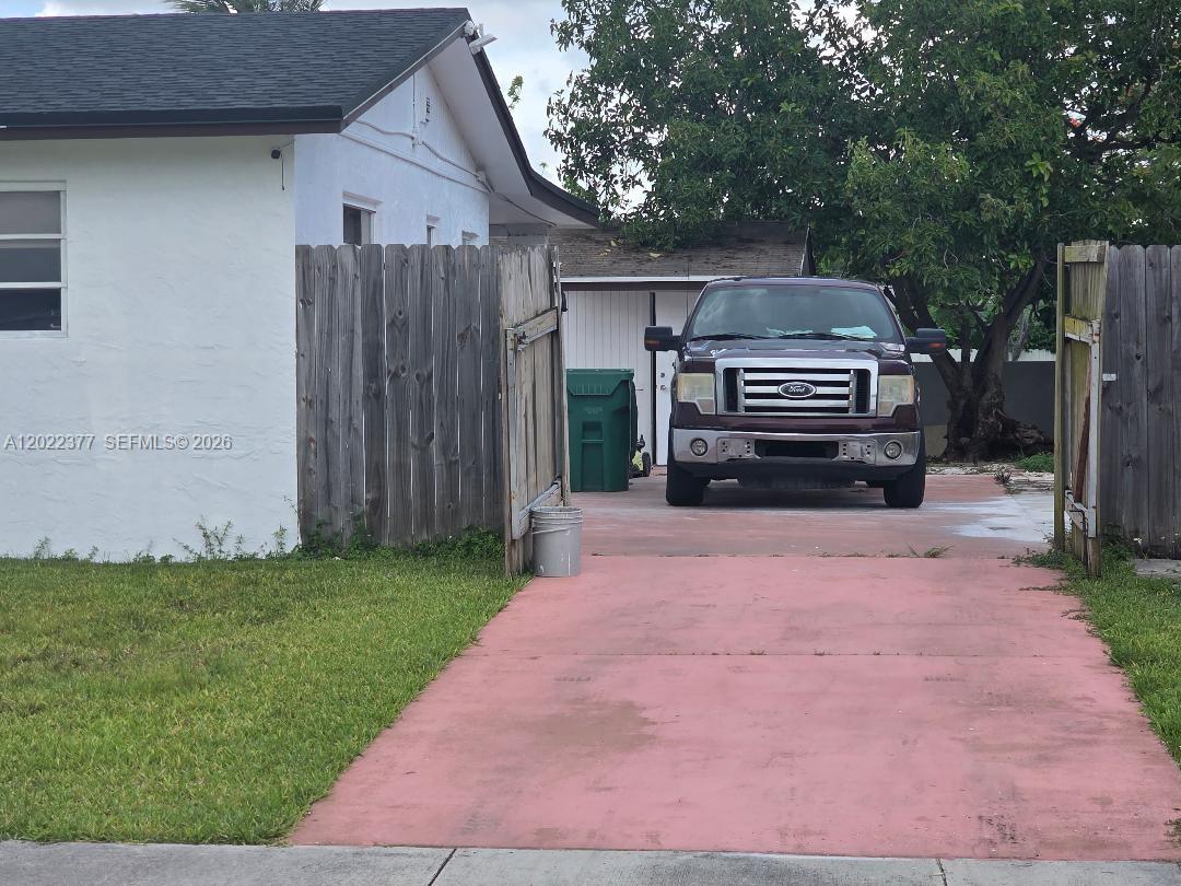A red concrete driveway leads to a parked truck in front of a white house — HOMESTEAD, FL