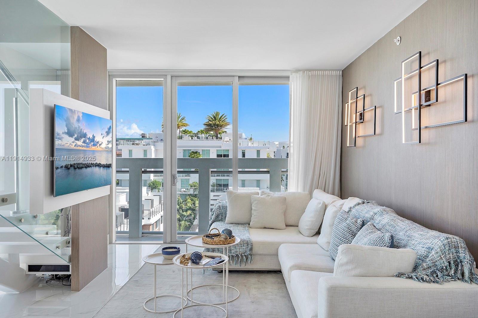 A modern living room features a white sectional sofa, nested coffee tables, and wall-mounted lighting — 1150 101st St # 701, Bay Harbor Islands FL 33154, BAY HARBOR ISLANDS, FL