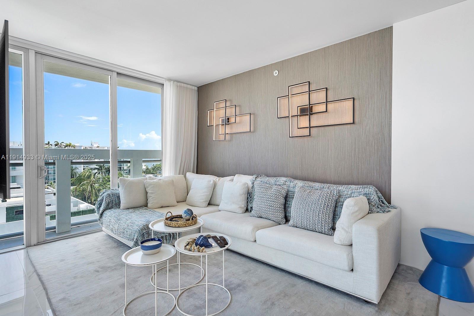 A living room features a white sectional sofa, nested coffee tables, and geometric wall art — 1150 101st St # 701, Bay Harbor Islands FL 33154, BAY HARBOR ISLANDS, FL