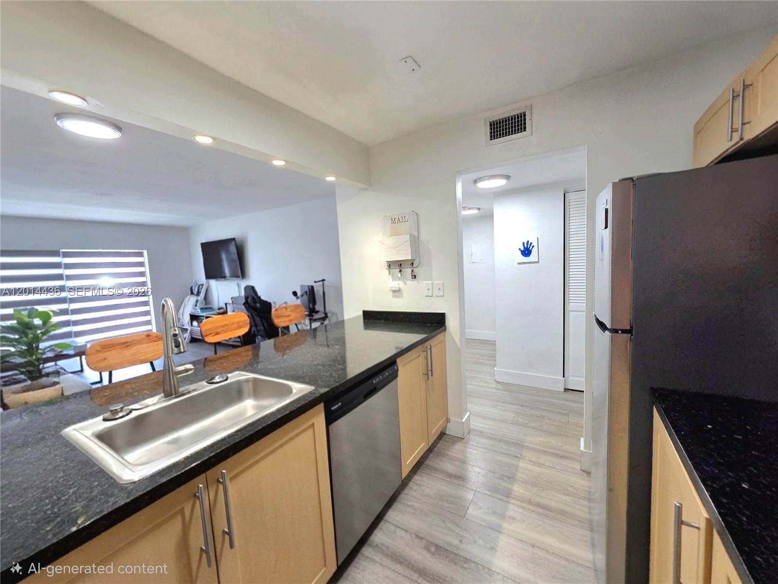 A kitchen features light wood cabinets, black countertops, stainless steel appliances, and wood-look flooring — 7477 SW 82nd St # C115, Miami FL 33143, MIAMI, FL