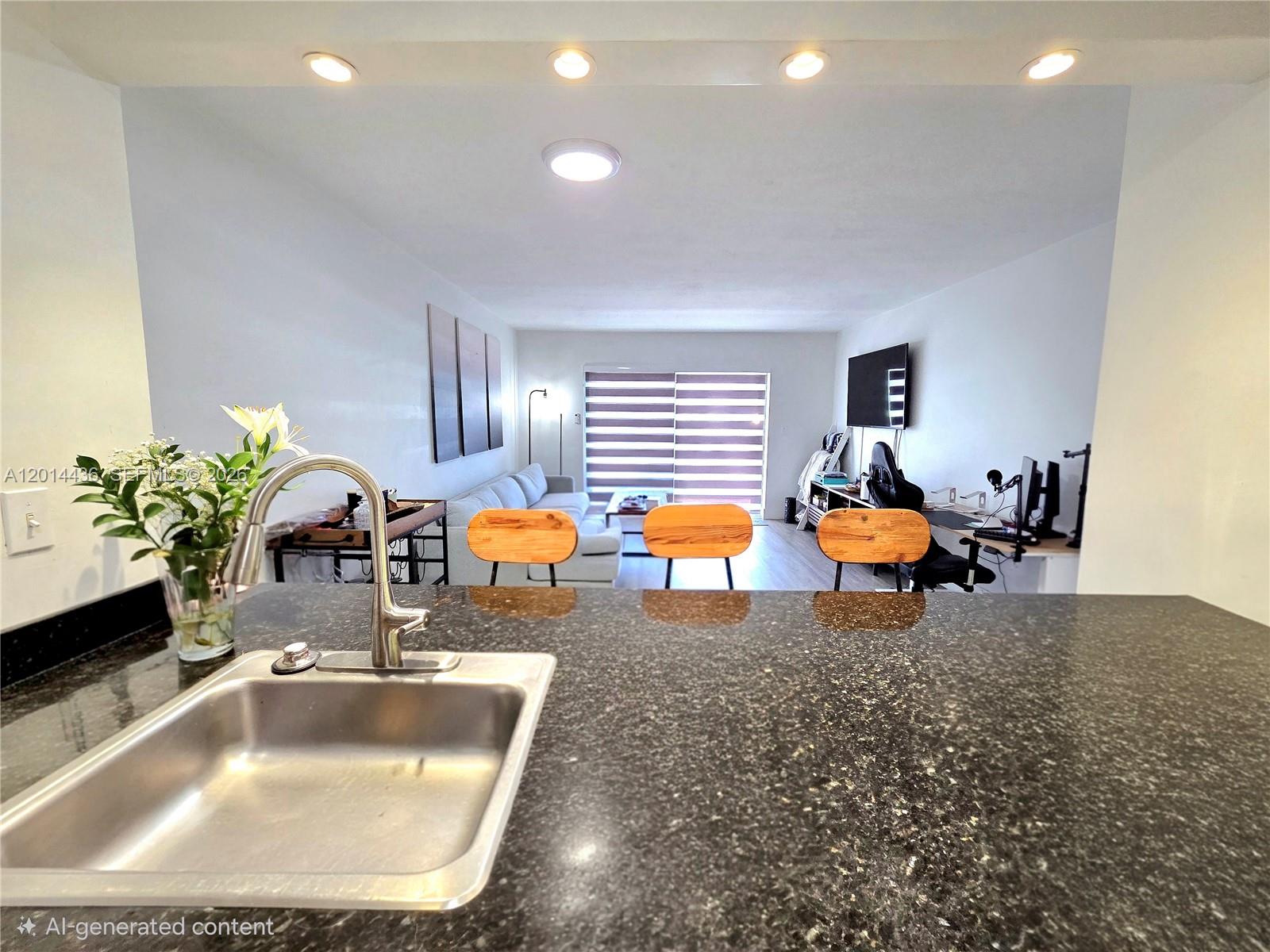 A kitchen sink with a dark granite countertop overlooks a living room and office area — 7477 SW 82nd St # C115, Miami FL 33143, MIAMI, FL