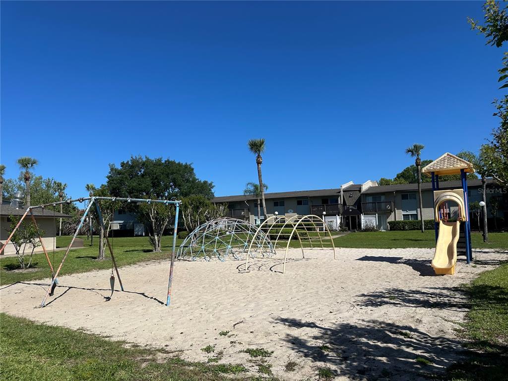 A playground with a swing set, climbing domes, and a slide sits on a sandy lot — 1695 LEE ROAD ROAD UNIT C110, WINTER PARK, FL