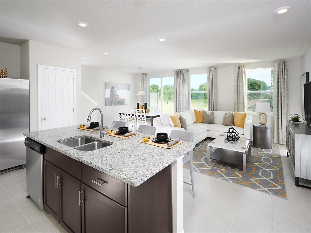 A kitchen island with granite countertops overlooks an open-concept living and dining area — 4557 RANGELAND WAY, ST CLOUD, FL