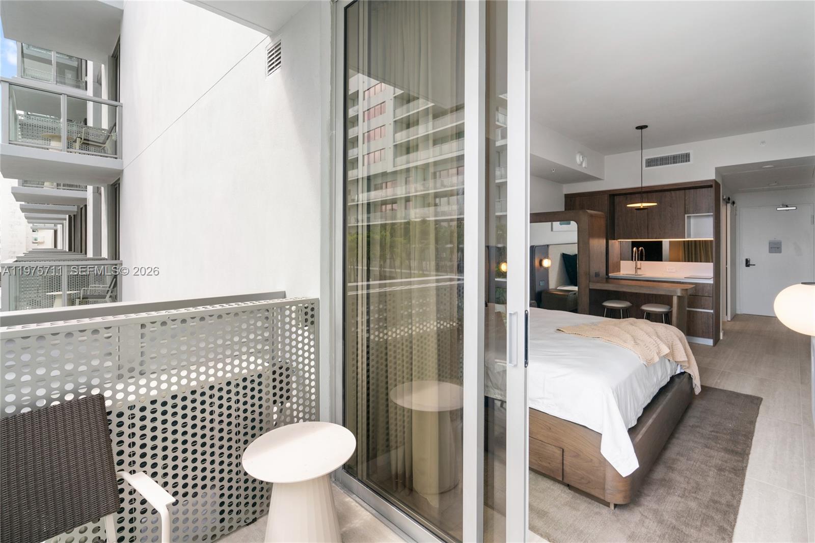 A bedroom with a kitchenette and balcony view through a sliding glass door — 1611 SW 2nd Av # 504, Miami FL 33129, MIAMI, FL