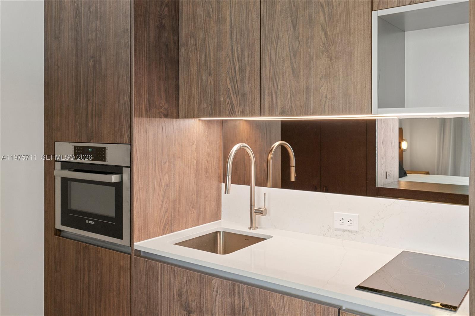 A modern kitchenette features wood-grain cabinetry, a white countertop, a sink, and a built-in microwave — 1611 SW 2nd Av # 504, Miami FL 33129, MIAMI, FL